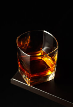 Glass of whiskey on a black table.
