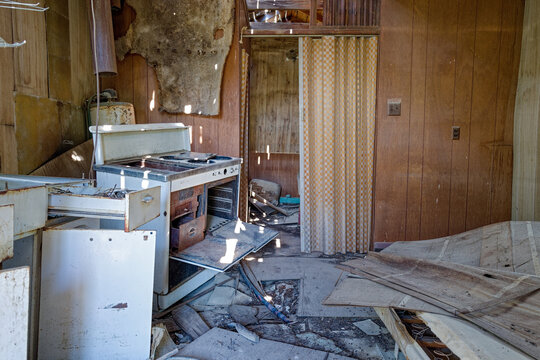 Sunlight through holes in the roof casts spots of light on the kitchen of an abandoned mining shack