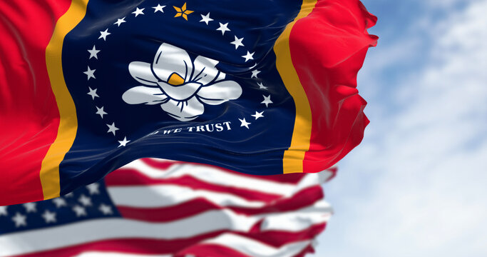 Mississippi state flags waving with the American flag on a clear day