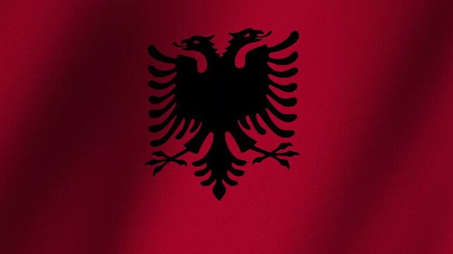 Albanian Flag Waving: A vibrant Albanian flag, predominantly red with a black double-headed eagle emblem, flutters dynamically, symbolizing national pride and heritage.