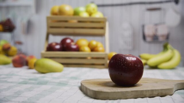 Juicy apple on cutting board near other delicious looking fruit, tracking shot