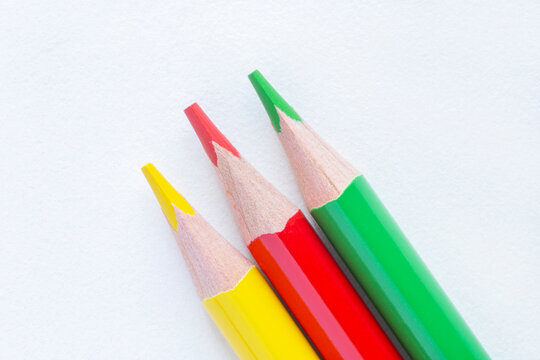 three color pencils laying on white sheet of paper