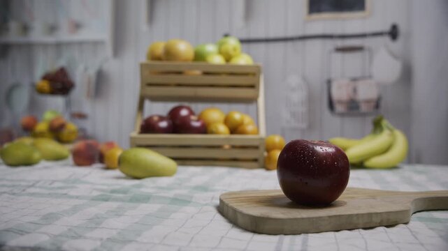 Moist red apple on counter near other yummy fruit, medium shot