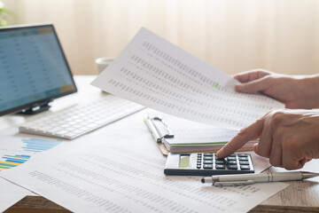 Obraz premium Hands performing essential accounting tasks, using a calculator and reviewing financial documents and data on a computer screen, signifying meticulous budgeting and reporting