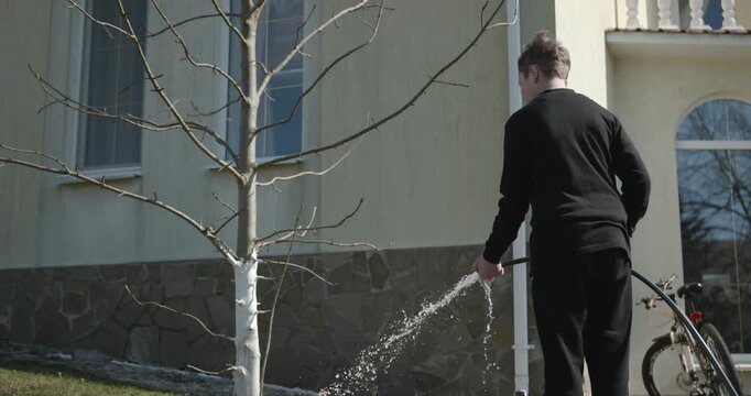 Kid Waters Plants in Garden Near House. Caucasian Boy Help Working Around Backyard. 4K 10-bit
