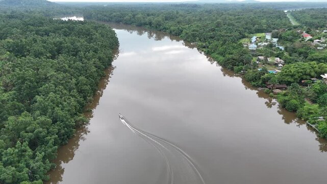 Aerial view of a speedboat navigating a wide tropical river near Roura, surrounded by dense rainforest in French Guiana.