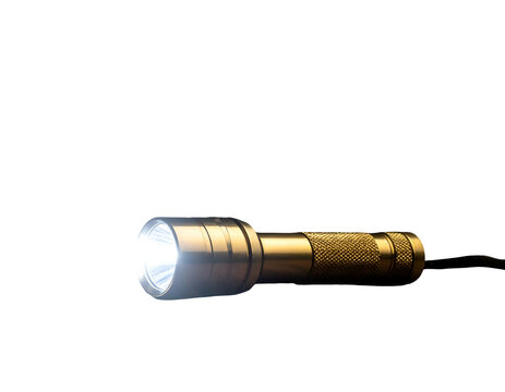A bright handheld metal flashlight glowing in the dark against black background