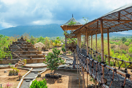 Bamboo treehouse and stone buddhist stupa in Tulamben, Bali, Indonesia with scenic mountain view of Agung volcano and tropical greenery. Sustainable architecture and rural adventure tourism location.