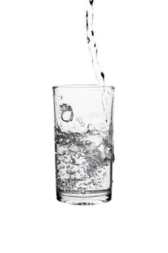 Pouring fresh drinking water into a clear glass isolated on a white background. Hydration, purity, refreshment, and healthy lifestyle concept.