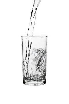 Pouring fresh drinking water into a clear glass isolated on a white background. Hydration, purity, refreshment, and healthy lifestyle concept.