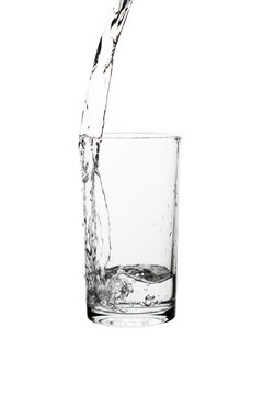 Pouring fresh drinking water into a clear glass isolated on a white background. Hydration, purity, refreshment, and healthy lifestyle concept.