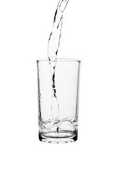Fresh water pouring into a clear drinking glass isolated on a white background.
