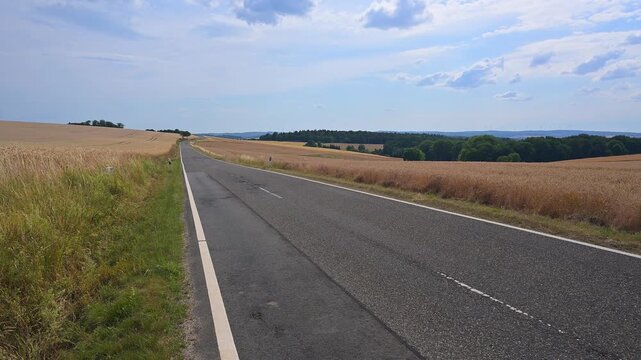 Einsame Landstra&szlig;e durch eine goldene Landschaft mit Getreidefeldern unter klarem Himmel, Beuerbach, H&uuml;nstetten, Taunus, Rheingau-Taunus-Kreis, Hessen, Deutschland