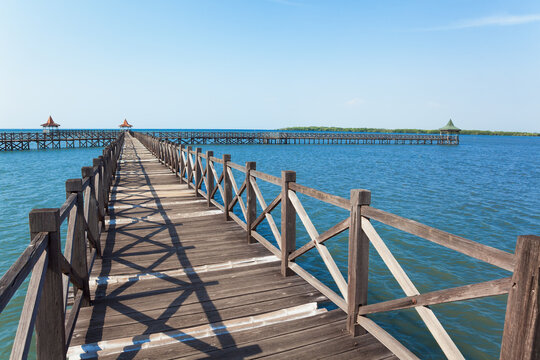 Long wooden pier with traditional gazebos - bale stretches over calm turquoise sea under clear blue sky. Perfect place for viewing amazing landscape.  Scenery for travel, resort, summer vacation