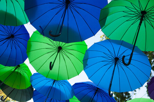 Blue and green umbrellas form a repeating overhead pattern, colorful outdoor decoration, creative festival background.