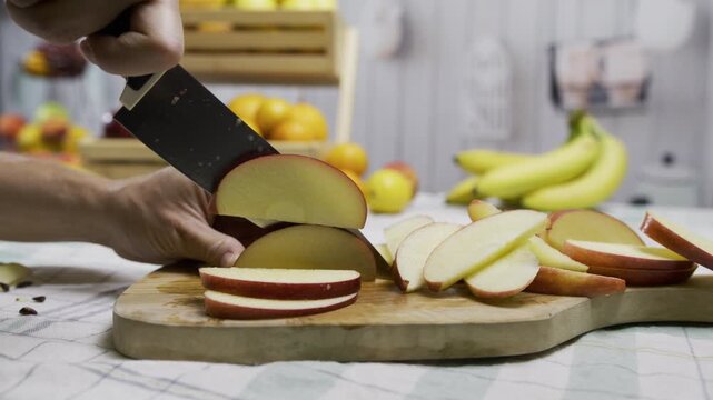 Sharp knife chopping red apple into slices on cutting board - closeup, tracking shot