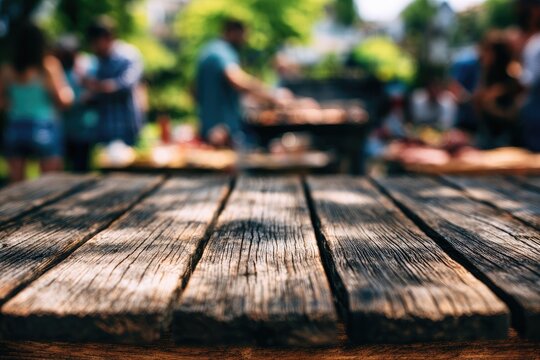 A rustic wooden table in foreground, blurred outdoor gathering with barbecue in background