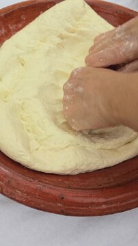 Close-up video of hands mixing and kneading dough ingredients in a traditional Moroccan clay bowl (Gsaa) to make dough for Rfissa.