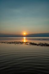 Obraz premium A serene golden sunset casting glowing reflections over the calm, shallow waters of Lake Constance as seen from the scenic Rohrspitz shore in Vorarlberg, Austria.