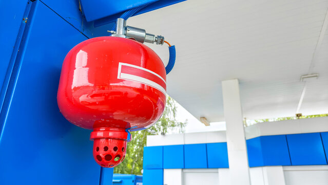 Fire extinguisher mounted at a gas station. Automatic fire suppression equipment for safety in hazardous fuel environment. Protection technology for petrol station management