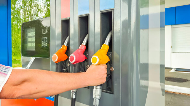 Man holding gas pump nozzle at self service filling station. Driver refilling car with fuel. Energy crisis and rising gasoline price concept. Industrial vehicle refueling process