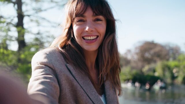 Video of cheerful woman doing videocall with smartphone in the park