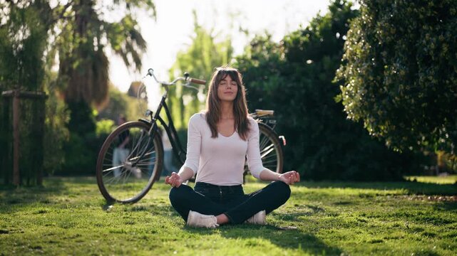 Video of pretty woman doing ioga while resting after cycling in the park.