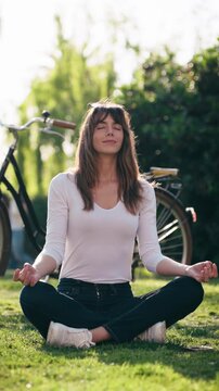 Video of pretty woman doing ioga while resting after cycling in the park.