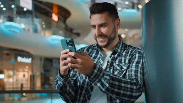 Happy smiling Caucasian business man guy using mobile phone social media scrolling online application smile cheerful male businessman browsing smartphone enjoying chatting web device in shopping mall