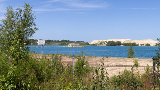 Lake Achterste Plas for sand extraction in Hoogersmilde in Drenthe,  Netherlands with danger sign,  blue water and sandy shore