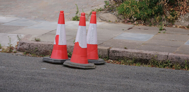 Traffic cones, orange safety cones on street, roadworks barrier on pavement in suburban street view