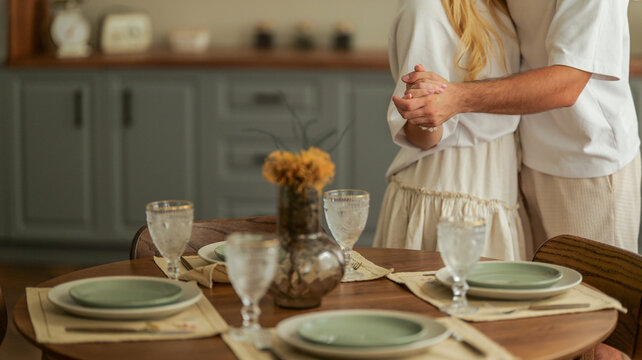 Couple holding hands and dancing at a beautifully set dining table for a romantic meal