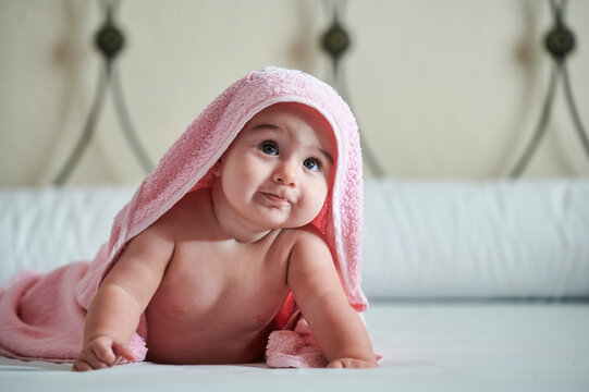 Little baby girl drying off with pink towel
