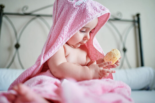 Baby girl playing with natural sponge after bath