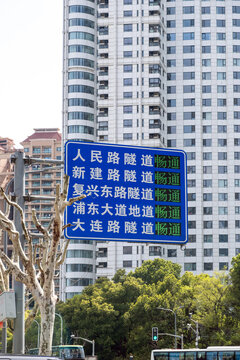 Tunnel route sign above bus road with trees near apartment towers in Shanghai, China