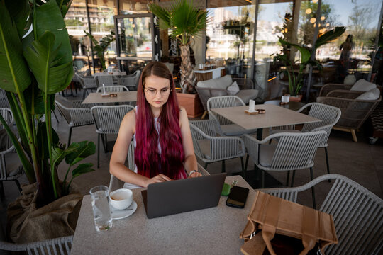 Young freelancer working on laptop at outdoor cafe terrace