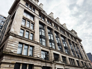 Obraz premium Historic stone office building with classical columns and large windows in Manchester, UK, urban commercial architecture under an overcast sky