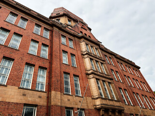 Obraz premium Historic red brick building facade and architecture with tower in Manchester, UK showing classic urban exterior and rows of windows