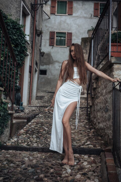 Young woman posing barefoot on cobblestone steps in Garda