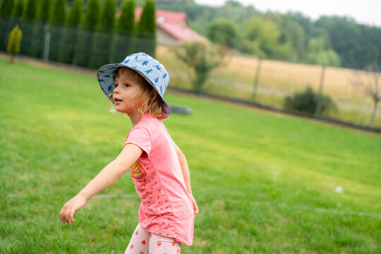Little Girl Walking Through Garden Wearing Sun Hat During Summer Outdoor Adventure