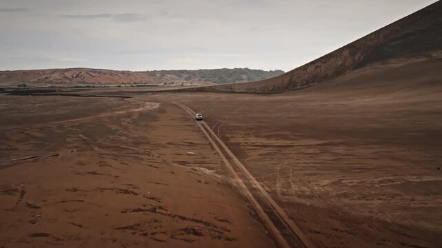 Off road vehicle driving along volcanic black sand track on Tanna Island, Vanuatu, symbolizing adventure, exploration, and isolation in rugged and dramatic natural landscape. Aerial view drone flight
