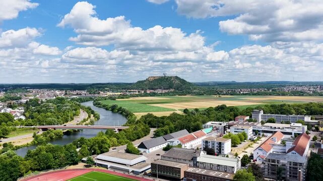 Vogelperspektive auf Saarlouis mit der vorbeiflie&szlig;enden Saar, einer markanten Stra&szlig;enbr&uuml;cke, dichter gr&uuml;ner Vegetation und der Stadtlandschaft unter blauem Wolkenhimmel.