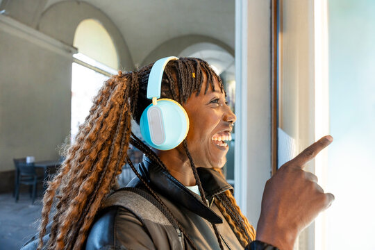 Gen Z woman smiling with headphones in bright corridor