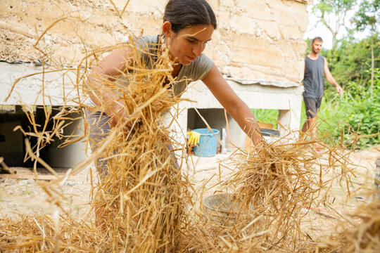 Woman preparing straw for sustainable house construction
