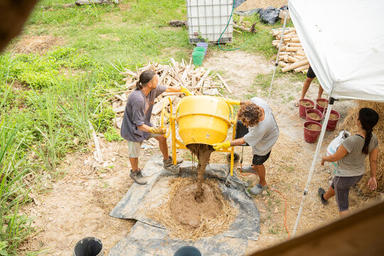 Team preparing clay mixture for sustainable house construction