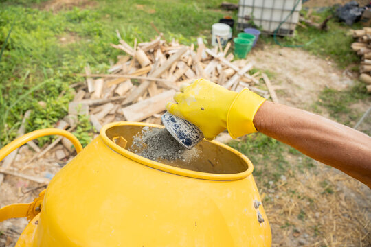 Worker adding mineral binder to mixer for natural construction