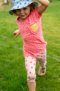 Little Girl Running Wearing Sun Hat During Summer Outdoor Play And Happy Childhood