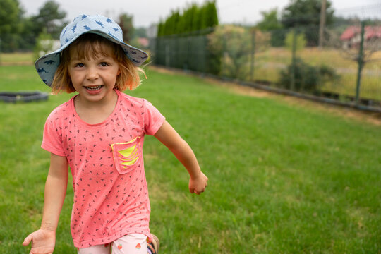 Happy Little Girl Running Toward Camera In Garden During Summer Outdoor Play