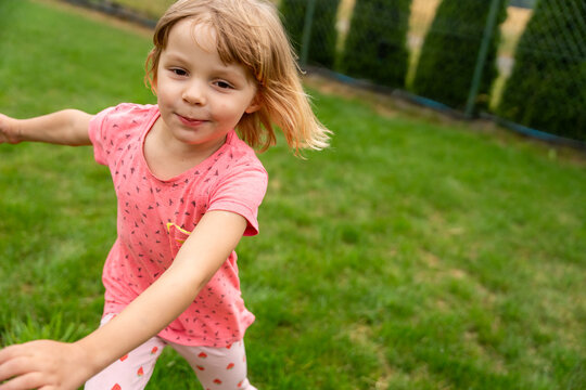 Little Girl Running And Reaching Forward In Garden During Summer Outdoor Play