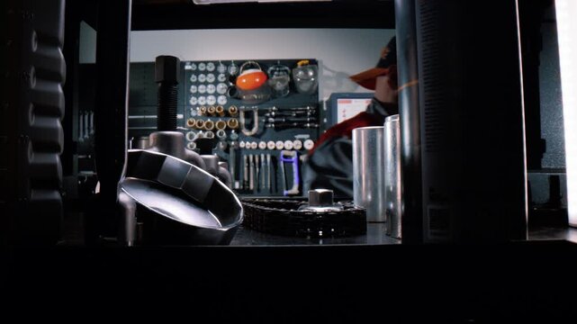 A bearded professional engineer takes a car repair tool from a shelf. A wide-angle macro shot 